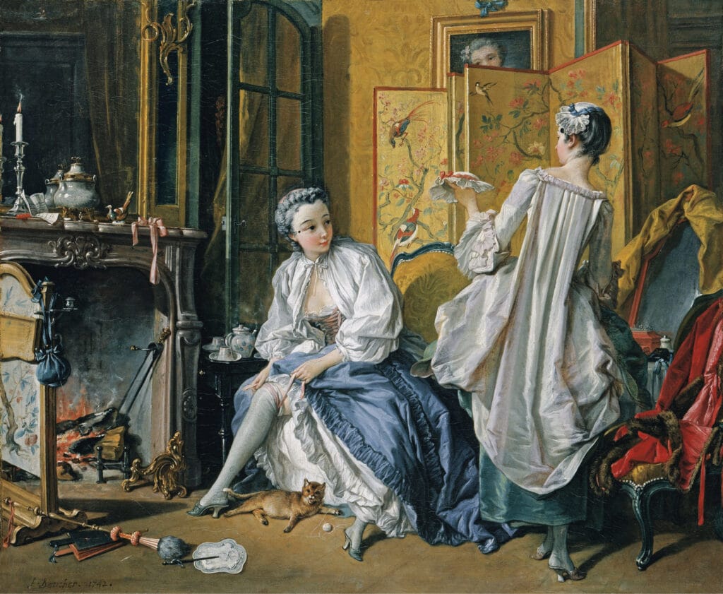 An elegant Rococo interior with a seated lady adjusting her stockings by the fireplace, while a maid presents a ribbon or bonnet. The room is richly decorated with a screen of painted birds, a playful cat, scattered accessories, and glowing firelight.